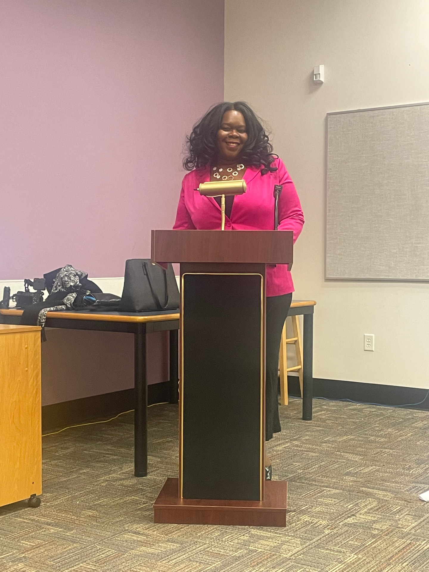 Marline Paul speaking from a lectern in a bright pink jacket at the Broward County Black Chamber of Commerce